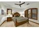 Cozy bedroom with a wooden bed frame, ceiling fan, and window with plantation shutters at 7780 E Golden Eagle Cir, Gold Canyon, AZ 85118