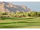 View of the green golf course, black and yellow pin and mountain views at Superstition Mountain Golf and Country Club at 7780 E Golden Eagle Cir, Gold Canyon, AZ 85118