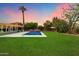 A stunning backyard features a pool, lush grass, and a beautiful sunset at 7813 N 17Th Dr, Phoenix, AZ 85021