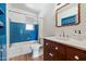 Bathroom features blue tiling in shower/tub area, warm vanity cabinet and a decorative mirror at 7813 N 17Th Dr, Phoenix, AZ 85021