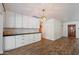 Bright kitchen with modern white cabinets, wood-look floors, black countertops and a decorative hanging lamp at 7813 N 17Th Dr, Phoenix, AZ 85021