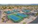 An aerial view of the community tennis courts with lush green surroundings and mountains in the distance at 8037 E Navarro Ave, Mesa, AZ 85209
