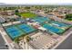 Aerial view of tennis courts with shade structures, seating, and a view of the desert community at 8037 E Navarro Ave, Mesa, AZ 85209