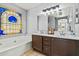 Bathroom with dual vanity, white countertops, and a soaking tub with decorative window at 8335 W Pershing Ave, Peoria, AZ 85381