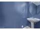 Modern powder room with blue walls, pedestal sink, oval mirror, and contemporary fixtures at 852 E Mountain View Rd # 18, San Tan Valley, AZ 85143