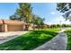 Charming home exterior with a well-kept lawn, mature trees, and a driveway leading to an attached garage at 945 N Pasadena -- # 62, Mesa, AZ 85201