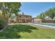 Expansive backyard featuring a sparkling pool with fountains, green lawn, and covered patio at 9570 W Quail Track Dr, Peoria, AZ 85383