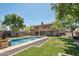 Spacious backyard with a pool featuring fountains, lush grass, and mature trees for privacy at 9570 W Quail Track Dr, Peoria, AZ 85383