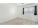 Minimalist bedroom with tile flooring and black out curtains, showcasing neutral tones at 9704 W Cordes Rd, Tolleson, AZ 85353