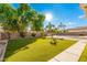 Beautiful backyard features lush synthetic grass and mature trees, creating a serene outdoor living space at 1779 E Kaibab Dr, Chandler, AZ 85249