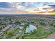 Expansive aerial view of a community showcasing a central pond, pool area, and surrounding residential neighborhood at sunset at 4615 E Calistoga Dr, Gilbert, AZ 85297