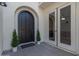 Elegant arched front door with decorative potted plants and sidelight, offering a warm welcome to visitors and residents alike at 4615 E Calistoga Dr, Gilbert, AZ 85297
