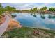 Serene pond view featuring lush landscaping, a paved walkway, and open-air gazebos creating a tranquil community setting at 4615 E Calistoga Dr, Gilbert, AZ 85297