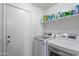 Efficient laundry room featuring a white washer, dryer, shelving, and a door at 10417 W Pioneer St, Tolleson, AZ 85353