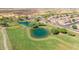 An aerial view shows a green golf course with a scenic pond with trees and residential homes nearby at 11250 E Kilarea Ave # 276, Mesa, AZ 85209