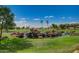 Scenic view of golf course pond with rock waterfall feature and palm trees against a clear blue sky at 11250 E Kilarea Ave # 276, Mesa, AZ 85209