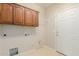 Laundry area with upper wood cabinets, utility sink hook-ups, and a white door to the exterior at 11250 E Kilarea Ave # 276, Mesa, AZ 85209