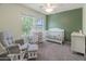 Bright Bedroom with crib, changing station, rocker, and lots of natural light from large windows at 13434 W Rovey Ave, Litchfield Park, AZ 85340