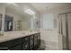 Bathroom featuring double vanity, tub, glass-enclosed shower, light, and neutral two-tone paint at 14897 W Valentine St, Surprise, AZ 85379