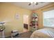 Bright bedroom features a ceiling fan, soft yellow walls, and ensuite bathroom access at 14897 W Valentine St, Surprise, AZ 85379