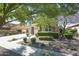Home with mature trees and shrubs surrounding manicured lawn provides shade and curb appeal at 14897 W Valentine St, Surprise, AZ 85379