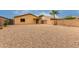 Xeriscaped backyard with a brick patio, covered porch, palm tree, and secure block wall at 16261 W Custer Ln, Surprise, AZ 85379