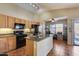 Modern kitchen with tile flooring, granite counters, island sink, black appliances, and wood cabinets at 16820 N 152Nd Ln, Surprise, AZ 85374
