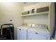 Functional laundry room with washer, dryer, storage shelves, and an ironing board at 1701 E Colter St # 488, Phoenix, AZ 85016