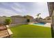 Backyard with sparkling pool, artificial turf, and block wall for privacy at 20233 E Maya Rd, Queen Creek, AZ 85142