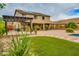 Lush backyard with pergola, outdoor kitchen, green grass, pavers and solar panels on the house roof at 26926 N 55Th Ln, Phoenix, AZ 85083