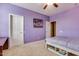 Comfortable bedroom featuring purple walls, carpeting, and two white doors to hall and closet at 26926 N 55Th Ln, Phoenix, AZ 85083