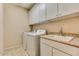 Functional laundry room featuring tile floor, laundry sink, cabinets, and appliances at 26926 N 55Th Ln, Phoenix, AZ 85083