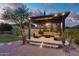 Inviting patio with a pergola featuring comfortable lounge seating surrounded by lush landscaping and ambient lighting at 26926 N 55Th Ln, Phoenix, AZ 85083