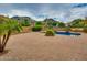 Expansive backyard showcasing a sparkling pool, patio, mature trees, and views of the surrounding mountains at 26926 N 55Th Ln, Phoenix, AZ 85083