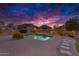 Stunning backyard pool with water feature, lush landscaping, and mountain views, enhanced by colorful sunset skies at 26926 N 55Th Ln, Phoenix, AZ 85083