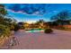Tranquil outdoor pool featuring ambient lighting, a lush garden, and a beautiful desert landscape at twilight at 26926 N 55Th Ln, Phoenix, AZ 85083
