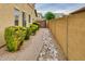 Landscaped side yard featuring lush green bushes, decorative stones, and a privacy fence for added seclusion at 26926 N 55Th Ln, Phoenix, AZ 85083