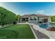 Well-manicured backyard with lush lawn, pool, rock waterfall, and an outdoor kitchen at 2721 E Tamarisk St, Gilbert, AZ 85296