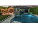 An outdoor view of a kidney-shaped pool that's surrounded by stone pavers and a gray house at 2721 E Tamarisk St, Gilbert, AZ 85296