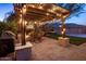 Outdoor dining area with pergola, string lights, a grill, and a view of the yard with a hammock and fire place at 2823 E Charlotte Dr, Phoenix, AZ 85024