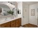Bathroom featuring double sinks, wood cabinets, modern lighting, decorative mirrors, a door, and a patterned backsplash at 2823 E Charlotte Dr, Phoenix, AZ 85024