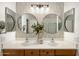 Bathroom featuring double sinks, wood cabinets, modern lighting, decorative mirrors and stylish patterned backsplash at 2823 E Charlotte Dr, Phoenix, AZ 85024
