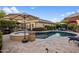Outdoor pool area with spa, fire pit and umbrellas, surrounded by lush landscaping and patio furniture at 2823 E Charlotte Dr, Phoenix, AZ 85024
