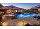 Outdoor pool area with spa, fire pit and umbrellas, surrounded by lush landscaping and patio furniture at dusk at 2823 E Charlotte Dr, Phoenix, AZ 85024