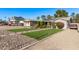 Well-kept front yard featuring artificial grass, flower bushes, solar panels, covered parking and desert landscaping at 3323 N 28Th St, Phoenix, AZ 85016