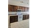 Bright kitchen featuring dark wood cabinets, white appliances and tile flooring under track lighting at 3454 E Bellerive Pl, Chandler, AZ 85249