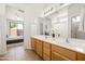 Bright bathroom featuring dual sinks with vanity, updated lighting, and walk in closet at 3756 E Waite Ln, Gilbert, AZ 85295
