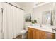 A well-lit bathroom featuring a single sink vanity and a shower with a white curtain at 3756 E Waite Ln, Gilbert, AZ 85295