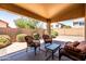 Charming covered patio with comfortable wicker furniture and hardscape surrounded by block fence and green landscaping at 4024 E Maplewood St, Gilbert, AZ 85297
