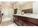 Bathroom featuring a bathtub with shower, double sinks and vanity with brown wood cabinets at 42109 N Astoria Way, Anthem, AZ 85086